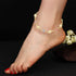 A foot adorned with the Good Luck Elephant Bracelet, featuring multicolor birthstones and small elephant charms. The foot, with red nail polish, is angled slightly forward, creating a striking contrast against the black surface enhanced by white flowers.